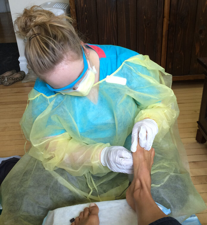 Owner of Kirsten's Foot Care providing nursing foot care on a client